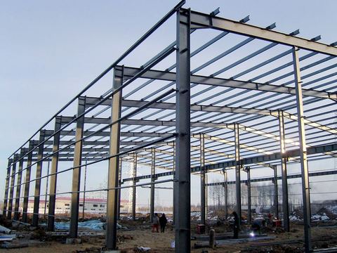 Struktur baja gudang industri dengan menara transmisi di latar belakang