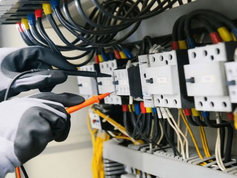 Teknisi melakukan pengukuran pada panel kontaktor