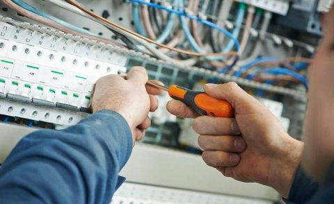 Teknisi memeriksa sambungan kabel pada panel distribusi