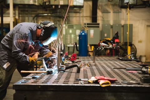 Pekerja mengelas di meja kerja workshop