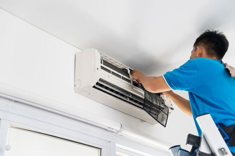 Teknisi membersihkan unit AC split