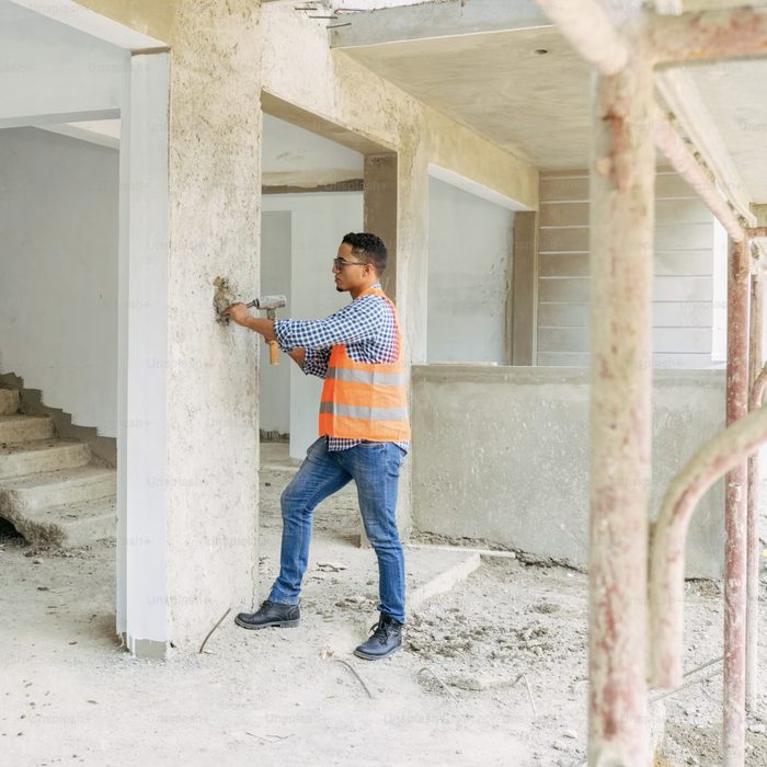 Pekerja mengerjakan finishing dinding bangunan